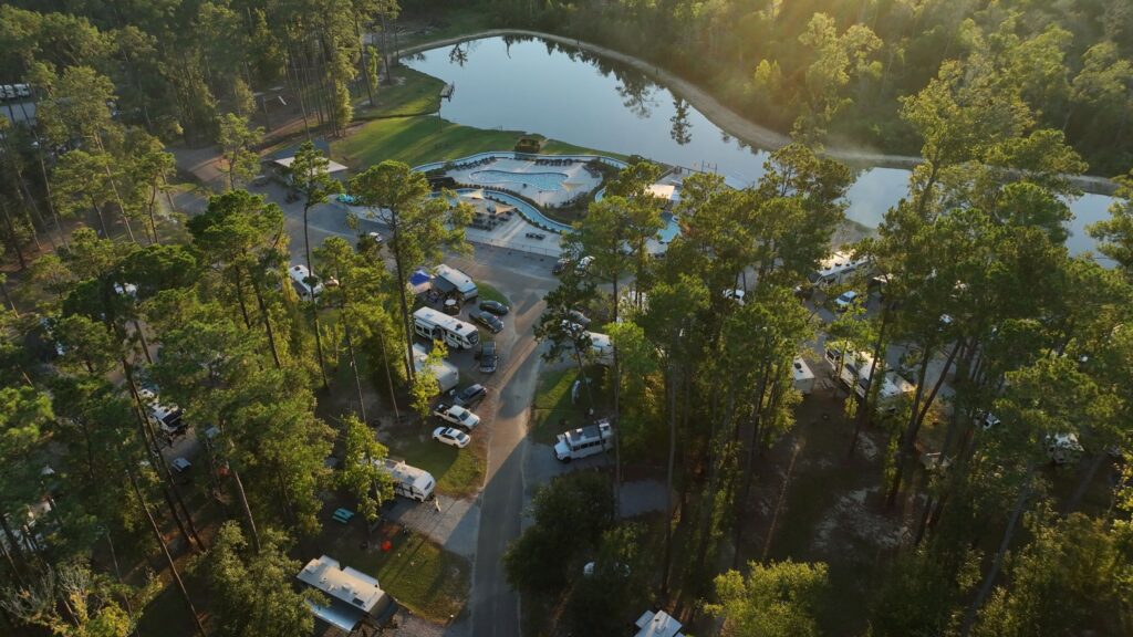 Aerial view of Fireside RV Resort at golden hour with its lake, pool, and shaded RV sites, a Northshore basecamp for LSU football weekends