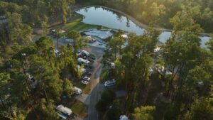 Aerial view of Fireside RV Resort at golden hour with its lake, pool, and shaded RV sites, a Northshore basecamp for LSU football weekends