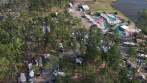 Aerial view of Fireside RV Resort grounds and lake surrounded by pine trees in Ponchatoula, Louisiana