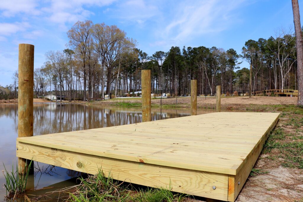 Wooden fishing dock reaching into a calm tree lined lake