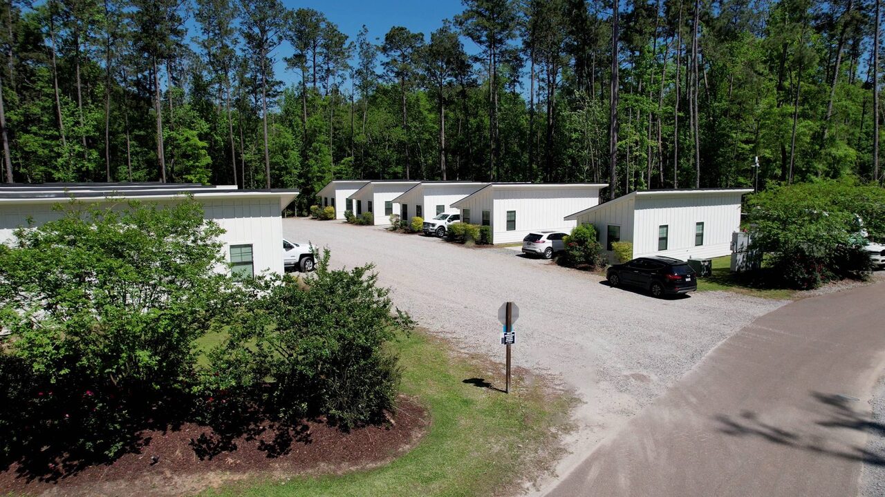 Row of furnished camping cabins under tall pines at Fireside RV Resort near New Orleans