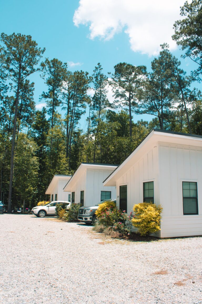 Row of white furnished glamping cabins under tall pines at Fireside RV Resort in Louisiana
