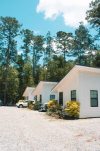 Row of white furnished glamping cabins under tall pines at Fireside RV Resort in Louisiana