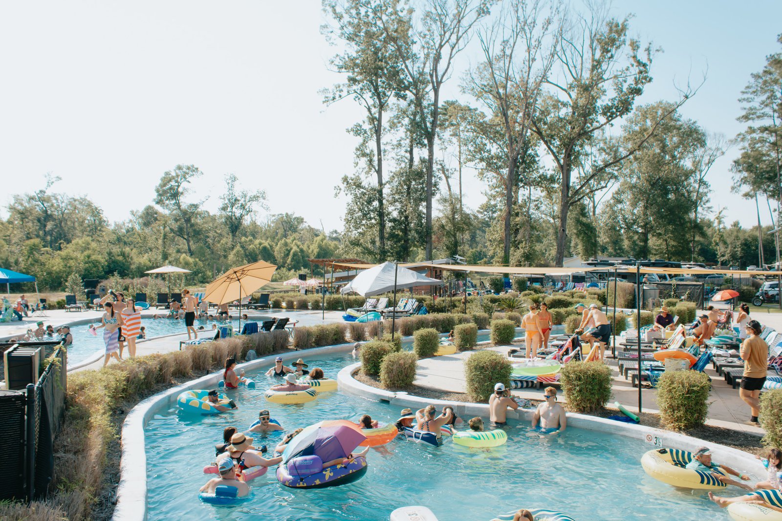 Families floating on tubes down the sunny lazy river at Fireside RV Resort in Louisiana