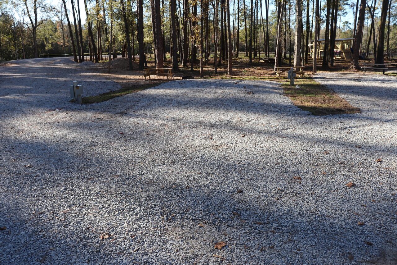Level full-hookup RV site with power water and sewer under shade trees at Fireside RV Resort