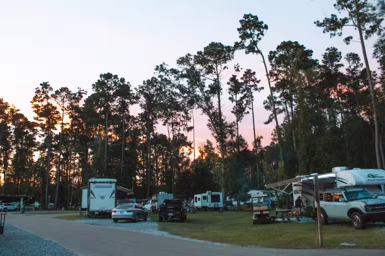 Sunset over spacious full-hookup RV sites among tall pines at Fireside RV Resort