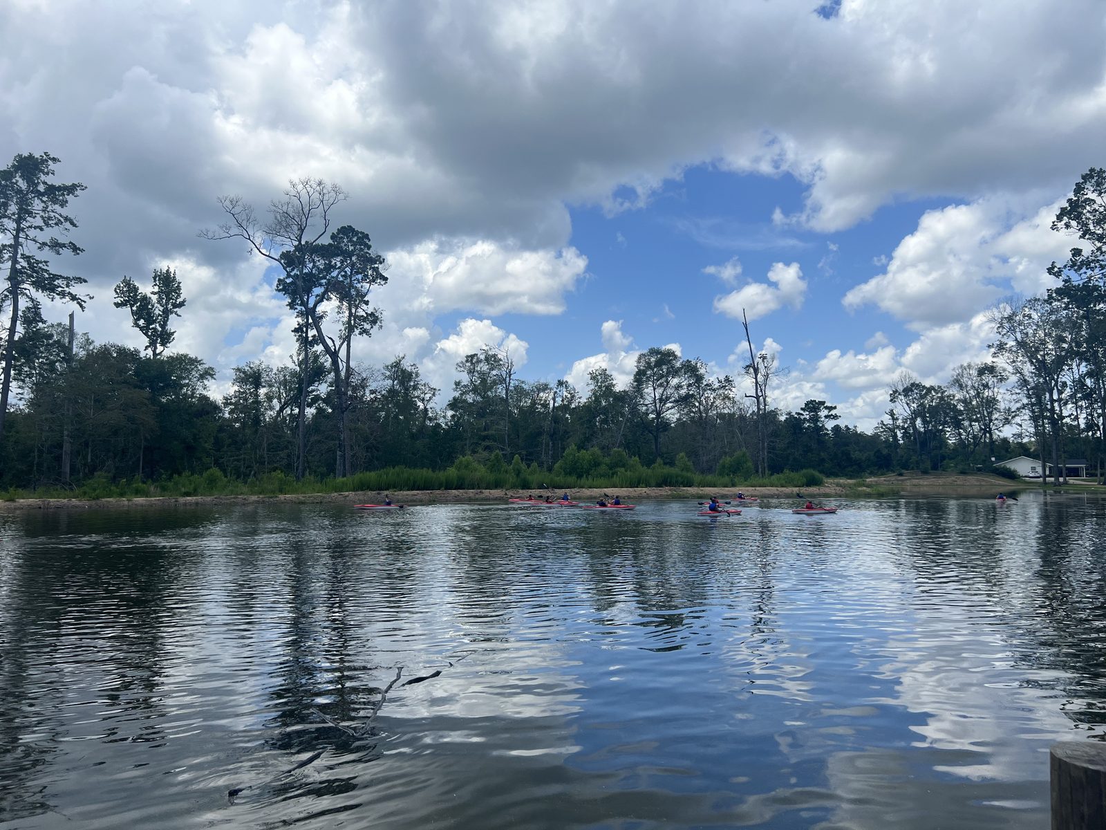 People kayaking on a calm pine-lined lake at Fireside RV Resort