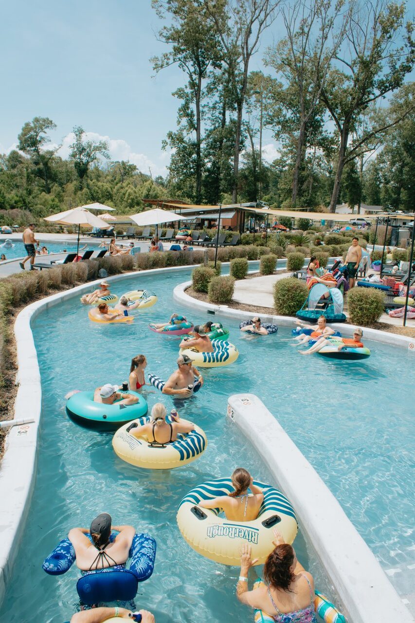 Guests floating on tubes down the lazy river at Fireside RV Resort on a sunny summer day