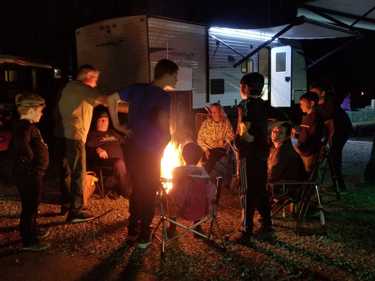 Guests gathered around an evening campfire beside an RV at Fireside RV Resort near New Orleans