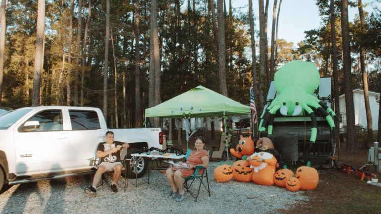 Couple relaxing in camping chairs beside their travel trailer and pickup at an extended stay RV park in Ponchatoula, Louisiana