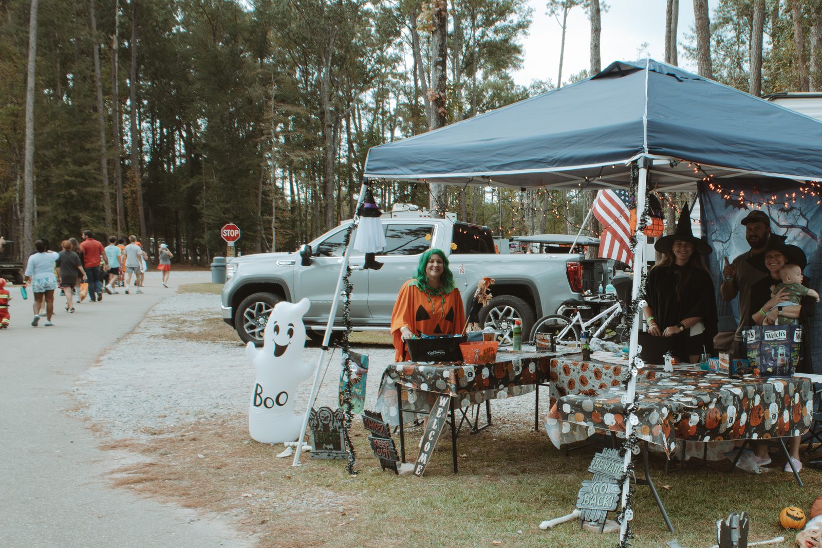 Campers in witch hats and costumes at a decorated canopy table beside a silver pickup at Fireside RV Resort in Ponchatoula