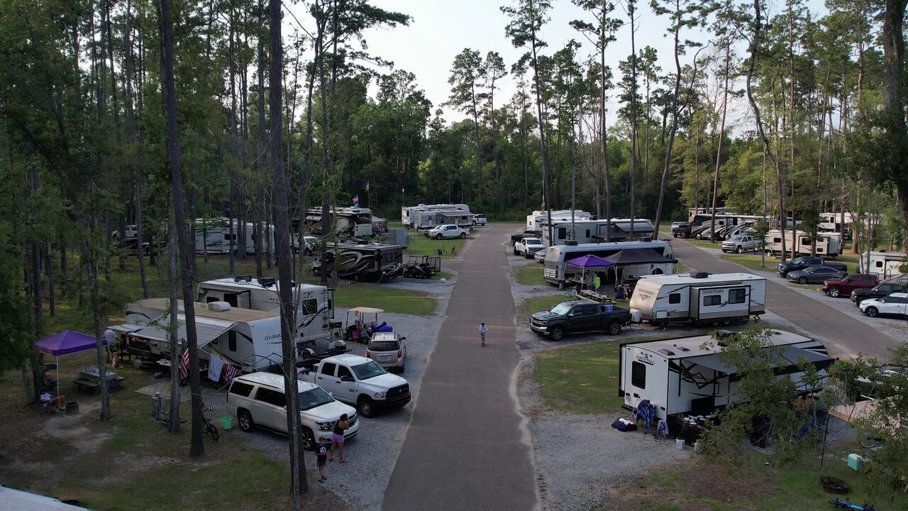 Overhead view of full hookup RV sites and a concrete road lined with campers and pine trees in Ponchatoula, Louisiana