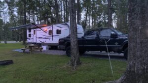 An RV set up with its awning out on a shaded site at Fireside RV Resort near New Orleans