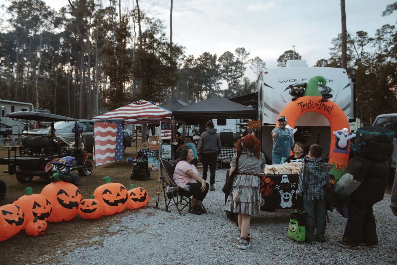 Families trick-or-treating past a Trick or Treat archway at a Louisiana RV campground Halloween weekend