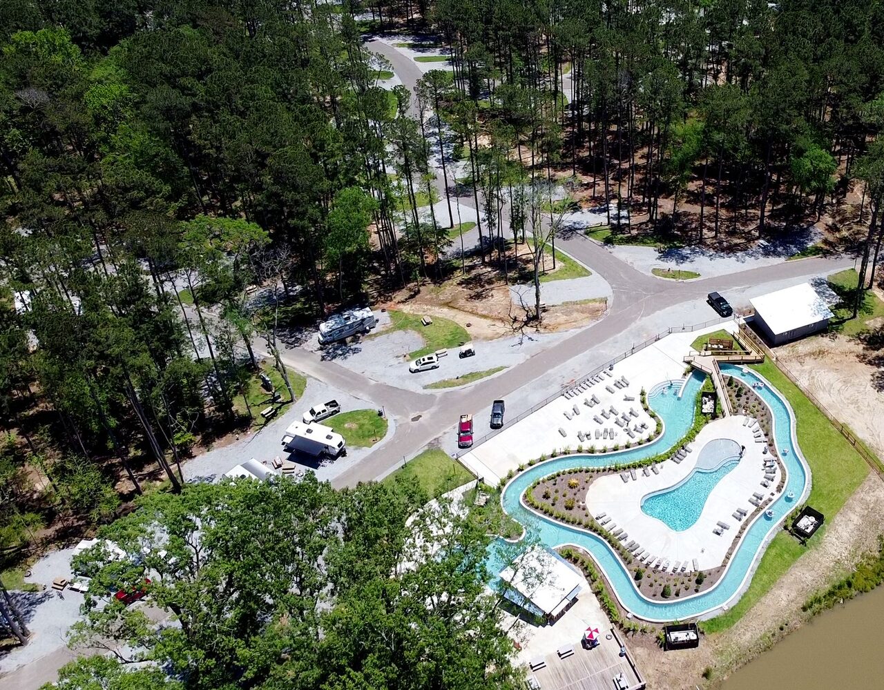 Aerial view of the lazy river, pool and pine-shaded RV loops at Fireside RV Resort, a pet friendly RV park in Ponchatoula, Louisiana