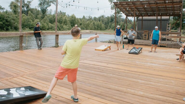 Guests playing cornhole on the lakeside deck at Fireside RV Resort in Ponchatoula, a short drive from Kliebert & Sons gator tours
