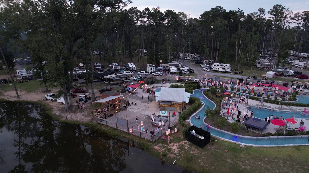 Aerial view of the lazy river, pool deck and pine-shaded RV sites at Fireside RV Resort near Ponchatoula, Louisiana