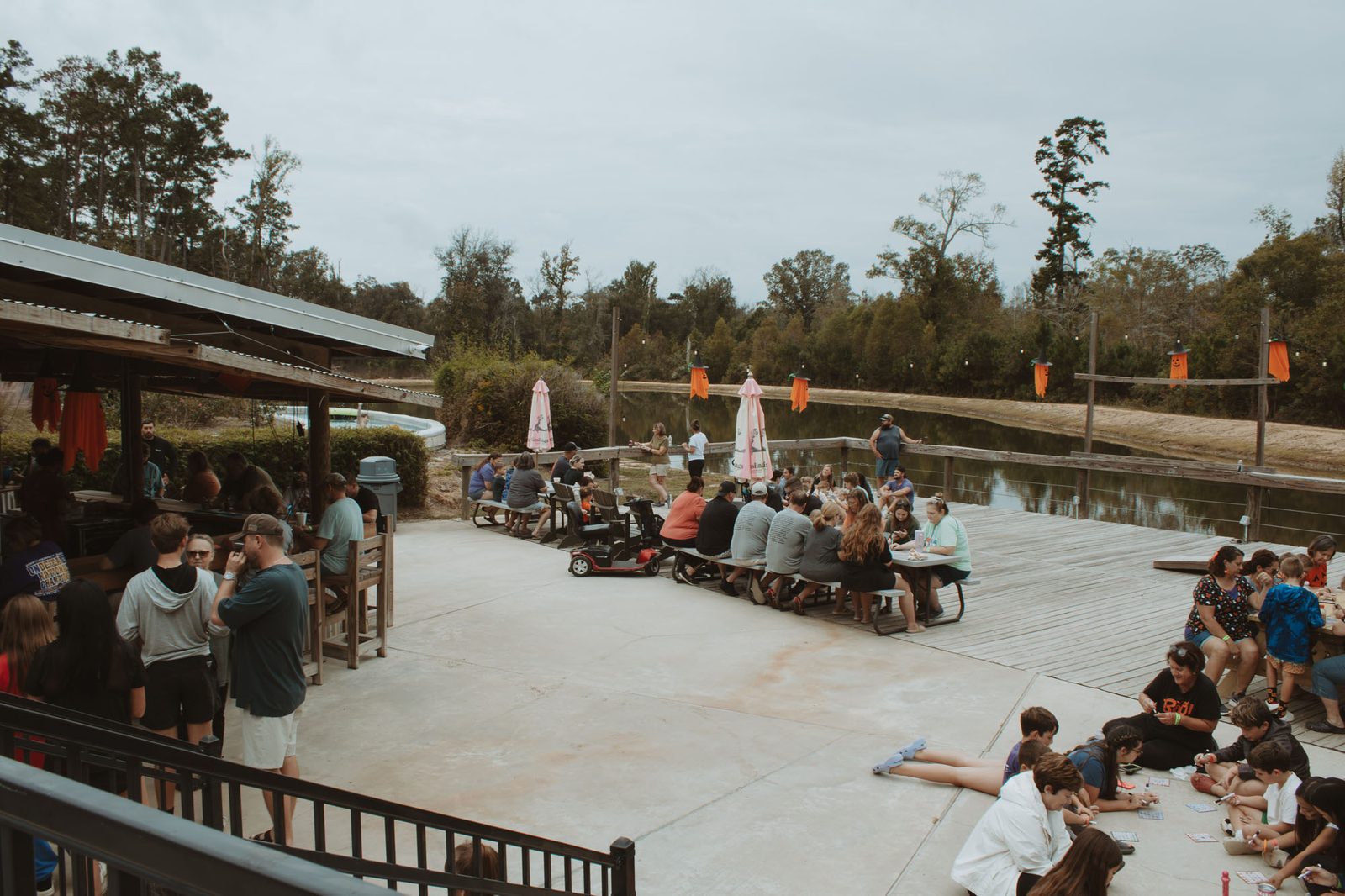 Families playing bingo at picnic tables and on the patio beside the pond at Fireside RV Resort in Ponchatoula, Louisiana