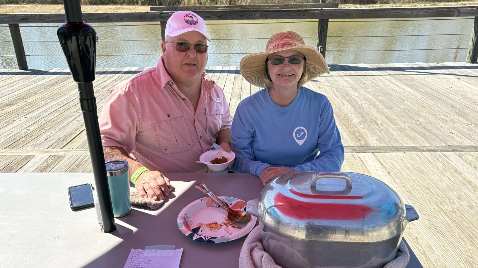 A couple seated at a table on a lakeside deck at Fireside RV Resort, a winter RV destination near New Orleans