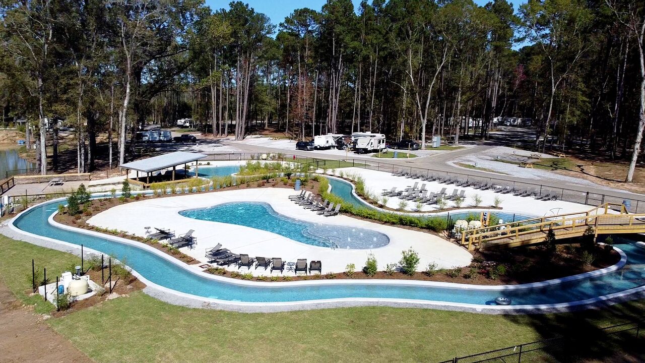 Aerial view of the lazy river curving around the family pool and sun deck at Fireside RV Resort, a full hookup RV park in Louisiana
