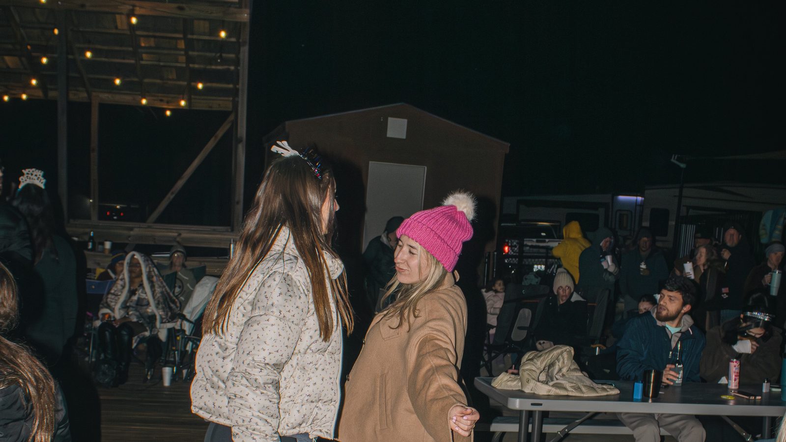 Two guests in winter jackets dancing under string lights at a New Year's Eve party at Fireside RV Resort in Ponchatoula