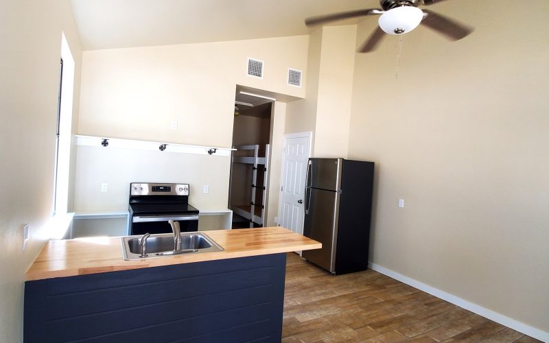 A bright, empty kitchen area featuring a dark blue island with a light wood countertop and stainless steel sink at Fireside RV Resort in Ponchatoula, Louisiana.